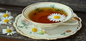 a cup of green tea with daisies off to the side