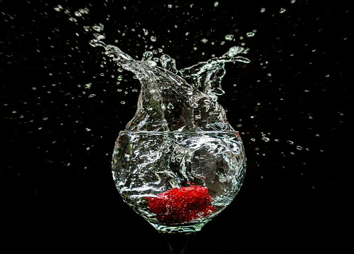 glass of water with strawberry just dunked in making a splash