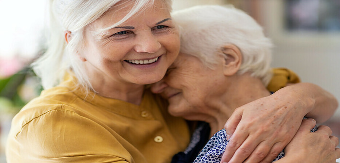senior woman embracing an elderly woman
