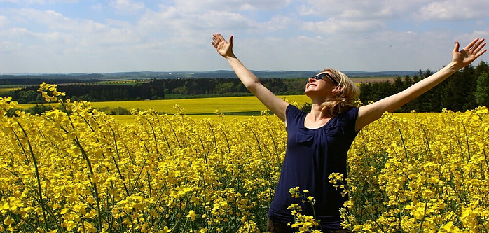 woman in field of wildflowers, arms outstretched, expressing gratitude